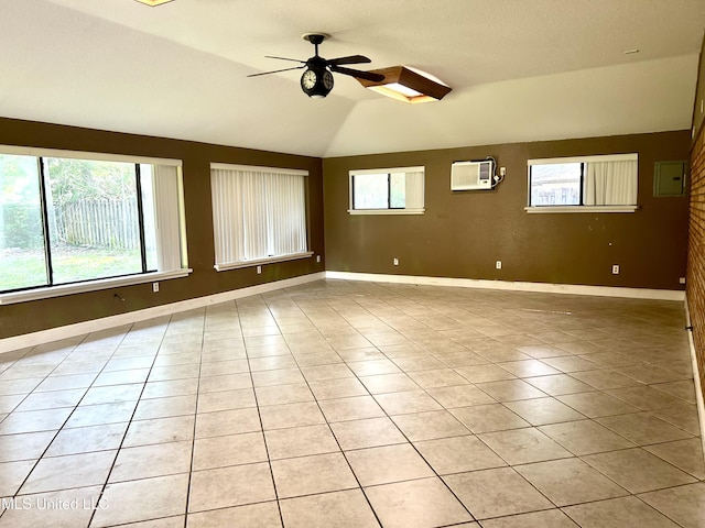 empty room featuring a healthy amount of sunlight, a ceiling fan, a wall mounted AC, and vaulted ceiling
