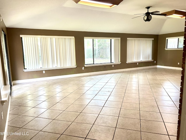 spare room featuring a ceiling fan, baseboards, vaulted ceiling, and light tile patterned floors