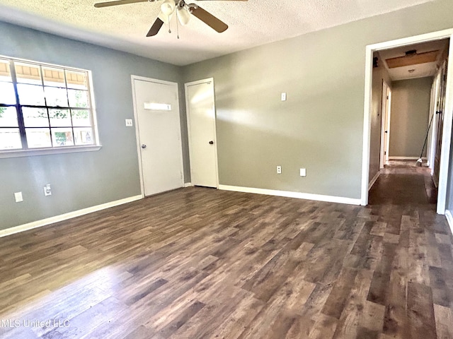 interior space with baseboards, a ceiling fan, dark wood-style flooring, and a textured ceiling