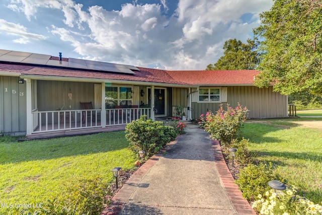 18153 Doc Lizana Rd, Gulfport, MS 39503 - ranch-style home featuring solar panels, a front yard, covered porch, and board and batten siding
