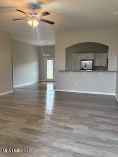 unfurnished living room with wood finished floors, a ceiling fan, and baseboards