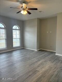 spare room with wood finished floors, a ceiling fan, and baseboards