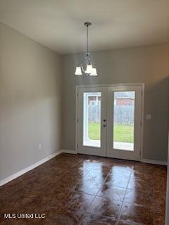 doorway to outside featuring baseboards, french doors, and a notable chandelier