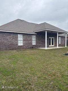 back of house featuring a yard, brick siding, and a patio