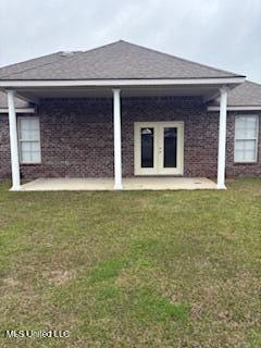 back of house featuring a shingled roof and a lawn