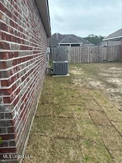 view of yard with central AC and fence