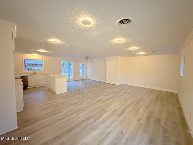 unfurnished living room featuring a textured ceiling, light hardwood / wood-style flooring, and ceiling fan