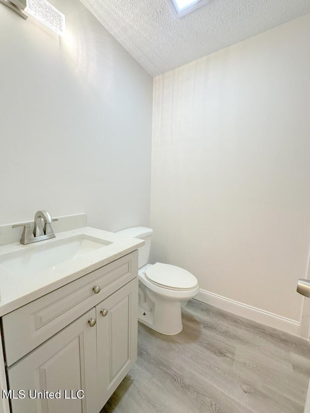 bathroom with a textured ceiling, vanity, hardwood / wood-style flooring, and toilet