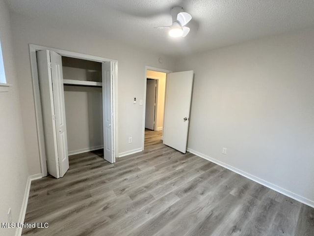 unfurnished bedroom featuring ceiling fan, light hardwood / wood-style floors, a textured ceiling, and a closet