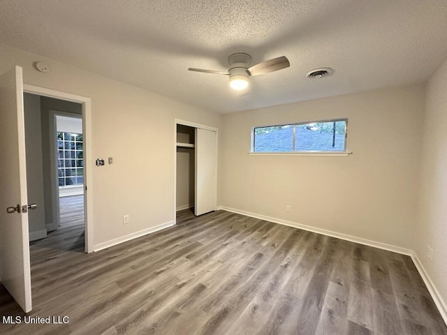 unfurnished bedroom with hardwood / wood-style floors, a textured ceiling, a closet, and ceiling fan