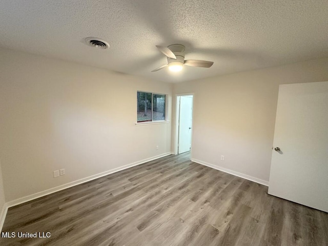 unfurnished room with ceiling fan, wood-type flooring, and a textured ceiling