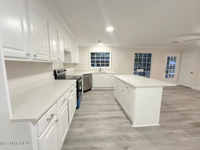 kitchen featuring a center island, white cabinetry, appliances with stainless steel finishes, and light hardwood / wood-style flooring