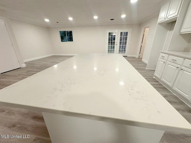 kitchen featuring dark hardwood / wood-style floors, a center island, light stone countertops, and white cabinetry