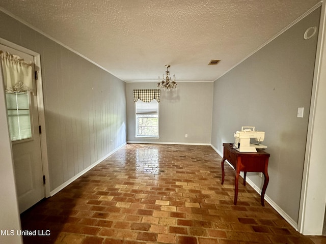 3427 Jr Davis Rd, Moss Point, MS 39562 - unfurnished dining area featuring a textured ceiling, brick floor, ornamental molding, and a notable chandelier