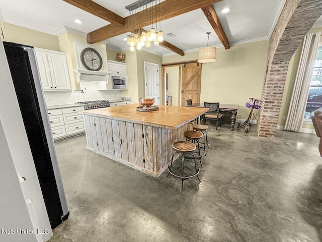 kitchen with a barn door, white cabinets, stainless steel microwave, a center island, and hanging light fixtures