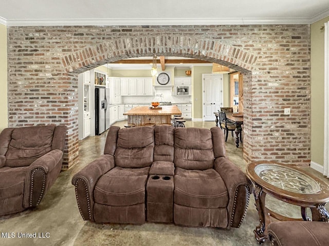 living room featuring baseboards, brick wall, arched walkways, and crown molding