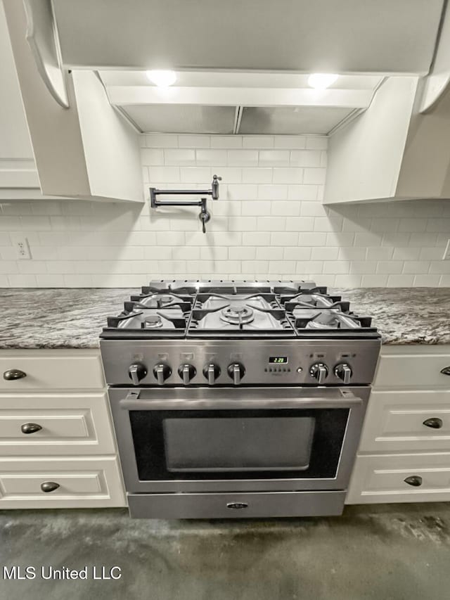 kitchen featuring tasteful backsplash, high end stainless steel range, light stone countertops, and white cabinets