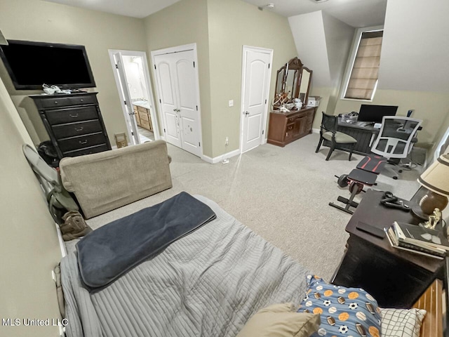 bedroom with light colored carpet, vaulted ceiling, ensuite bath, and baseboards