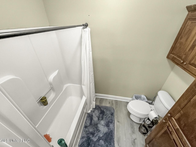 full bath with toilet, shower / bath combination with curtain, baseboards, and wood finished floors