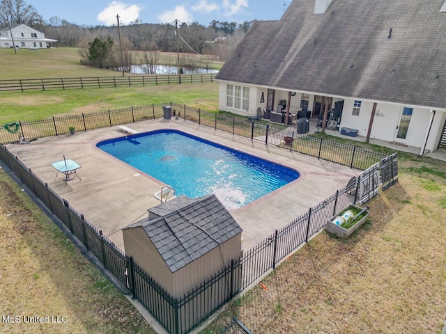 view of swimming pool featuring a fenced in pool, a patio, a water view, a lawn, and fence