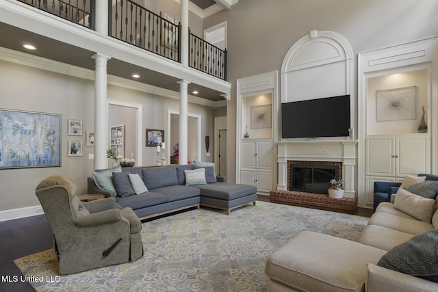 340 Sherborne Pl, Flowood, MS 39232 - living area with a towering ceiling, crown molding, decorative columns, dark wood-style flooring, and a fireplace