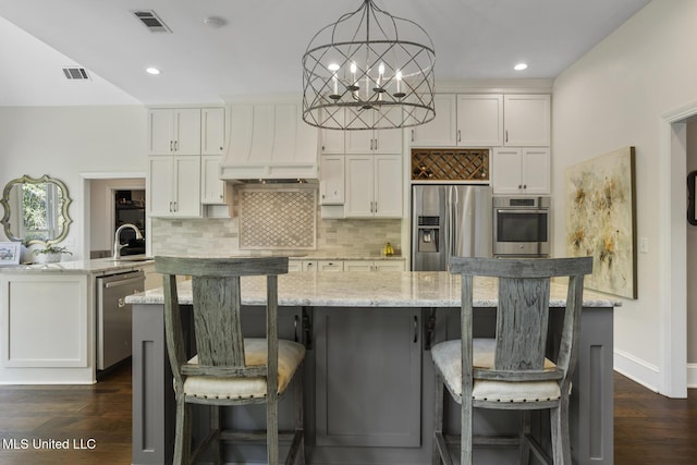 340 Sherborne Pl, Flowood, MS 39232 - kitchen featuring stainless steel appliances, an island with sink, custom exhaust hood, backsplash, and white cabinetry