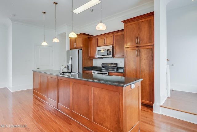 kitchen with a center island with sink, a sink, stainless steel appliances, light wood-style floors, and brown cabinetry