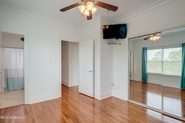 unfurnished room featuring crown molding, light wood-style flooring, baseboards, and ceiling fan