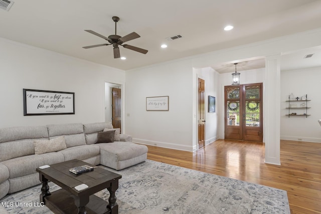 living area with visible vents, a ceiling fan, light wood-style flooring, and baseboards