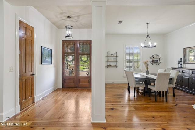 dining area featuring visible vents, crown molding, a notable chandelier, and hardwood / wood-style flooring