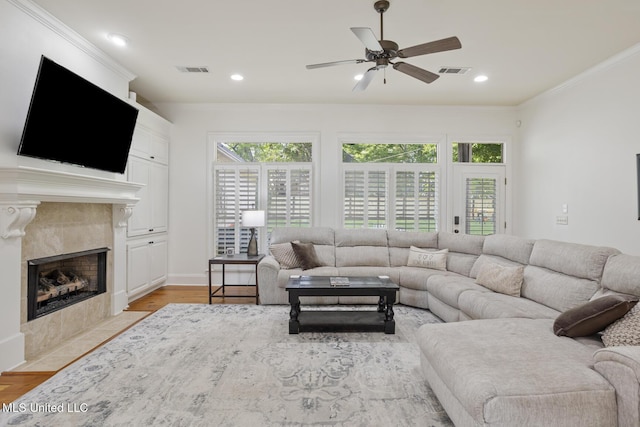 living room with ceiling fan, visible vents, ornamental molding, and a fireplace