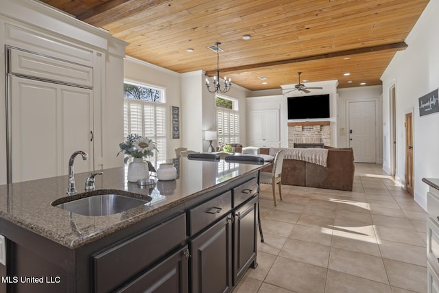 kitchen featuring a sink, a brick fireplace, ceiling fan with notable chandelier, and wooden ceiling