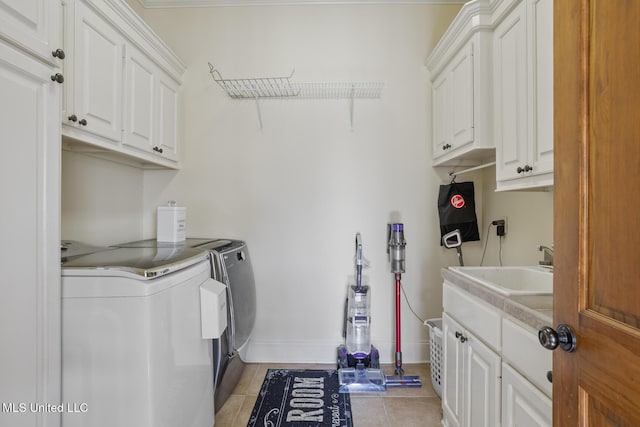 washroom with washing machine and clothes dryer, cabinet space, a sink, baseboards, and light tile patterned floors