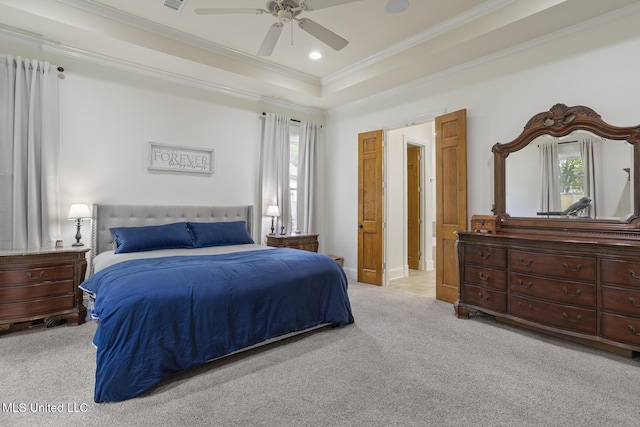 bedroom with a tray ceiling, light colored carpet, multiple windows, and ornamental molding