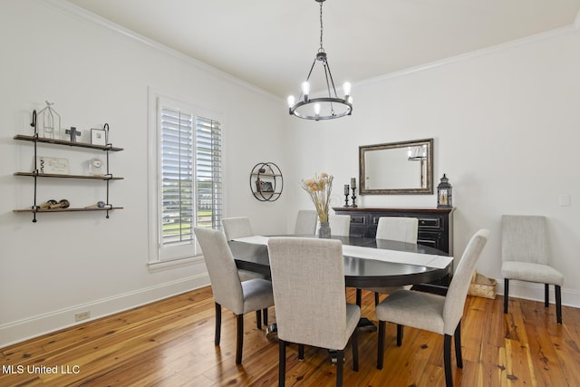 dining area with baseboards, ornamental molding, light wood-type flooring, and a notable chandelier