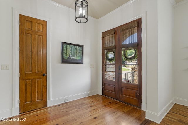 entryway featuring french doors, ornamental molding, light wood-style flooring, and baseboards
