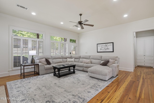 living room with a ceiling fan, visible vents, crown molding, wood finished floors, and baseboards