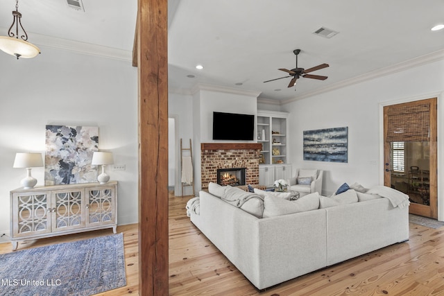 living area featuring visible vents, a fireplace, ornamental molding, and wood finished floors