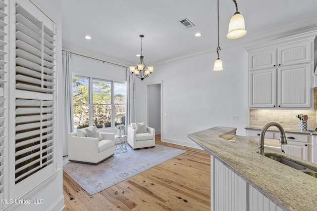 kitchen featuring tasteful backsplash, white cabinets, visible vents, and a sink