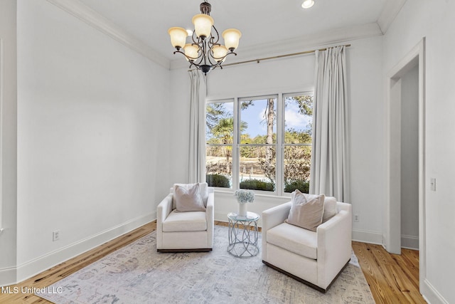 sitting room featuring baseboards, a notable chandelier, ornamental molding, and wood finished floors