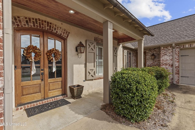 doorway to property with french doors, roof with shingles, an attached garage, and brick siding