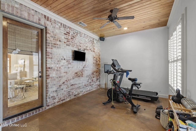 exercise area with brick wall, a ceiling fan, baseboards, wood ceiling, and crown molding