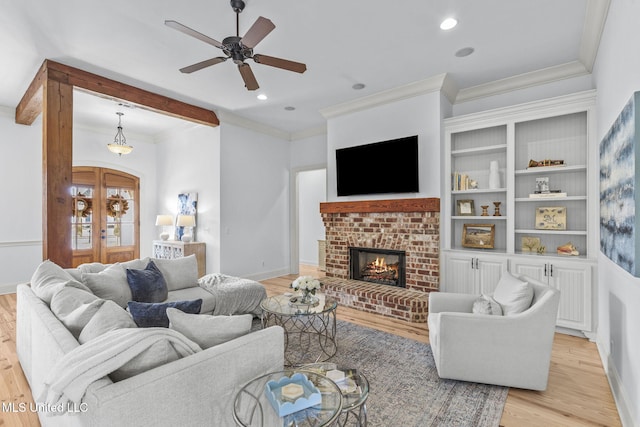 living room with light wood-style flooring, a fireplace, baseboards, ornamental molding, and french doors