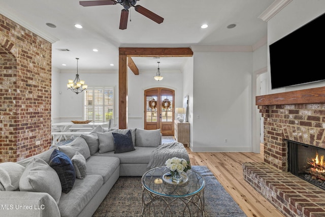 living room featuring light wood-type flooring, a fireplace, crown molding, and visible vents