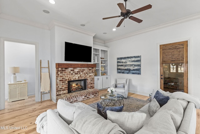 living room with a brick fireplace, crown molding, baseboards, and wood finished floors