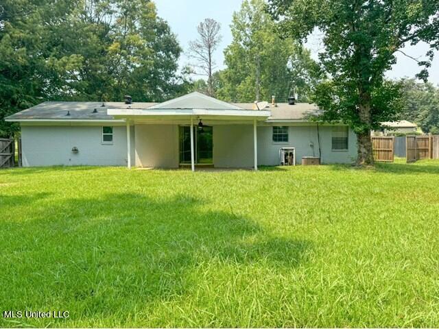 305 Longview St, Vicksburg, MS 39180 - back of house featuring fence, a lawn, and stucco siding