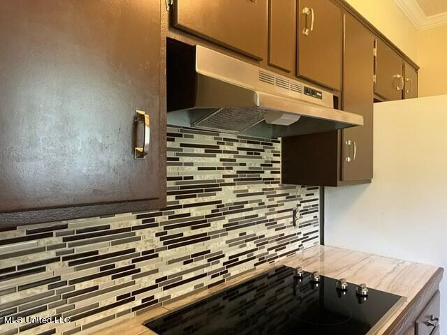 305 Longview St, Vicksburg, MS 39180 - kitchen with black electric cooktop, decorative backsplash, light countertops, under cabinet range hood, and ornamental molding