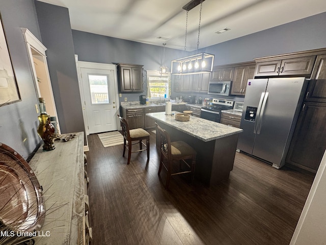 590 Eubanks Rd, Alligator, MS 38720 - kitchen featuring appliances with stainless steel finishes, a kitchen island, dark wood-style flooring, hanging light fixtures, and light stone counters
