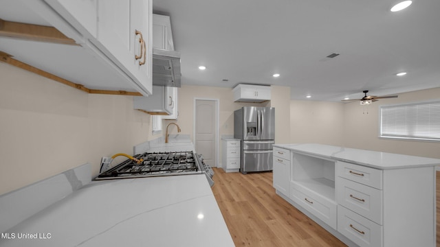 kitchen featuring light wood-type flooring, white cabinets, ceiling fan, and stainless steel appliances