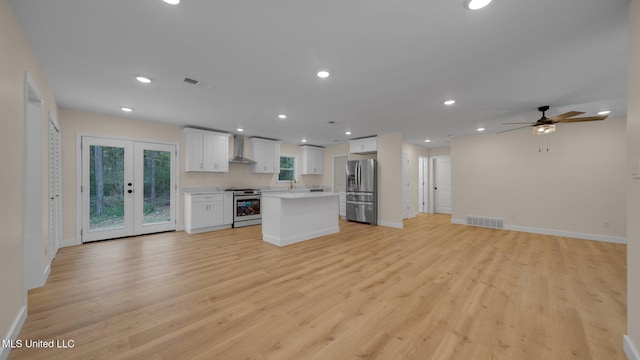 kitchen featuring stainless steel appliances, wall chimney exhaust hood, white cabinetry, and light hardwood / wood-style flooring